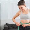 Smiling woman measuring waist after personalized weight loss care in Ellicott MD