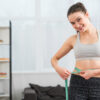 Smiling woman measuring waist after following weight loss solutions in Columbia