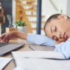 Woman asleep at her desk showing signs of fatigue from hormone imbalance symptoms