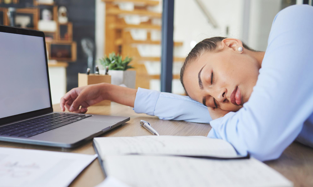 Woman asleep at her desk showing signs of fatigue from hormone imbalance symptoms