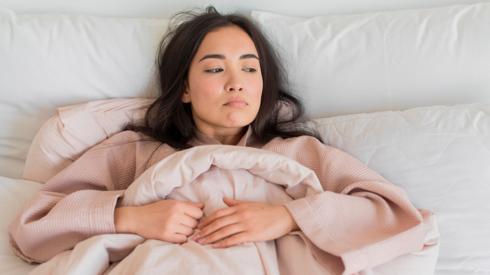 Woman lying in bed looking tired affecting weight loss and sleep