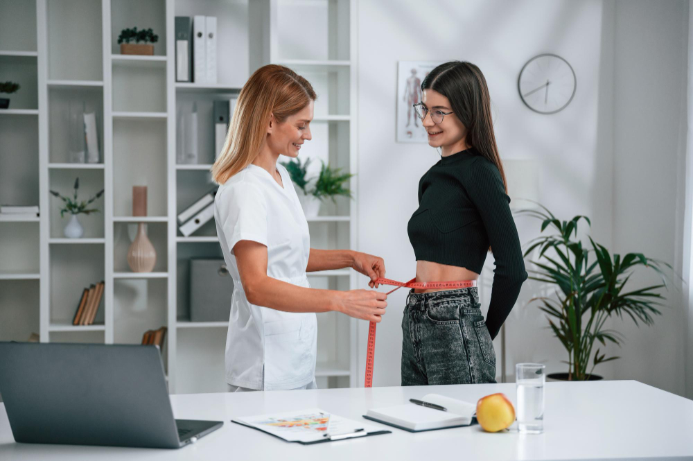 Medical provider measuring patient waist during a weight loss consultation