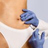 Medical provider in blue gloves administering weight loss injections into a patient's abdomen