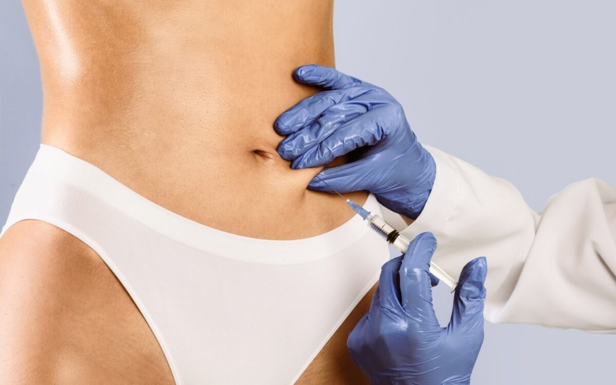 Medical provider in blue gloves administering weight loss injections into a patient's abdomen