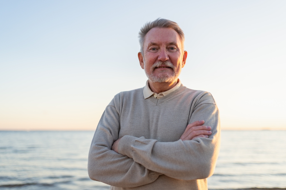 Confident older man standing outdoors with arms crossed representing a positive TRT timeline and testosterone replacement results