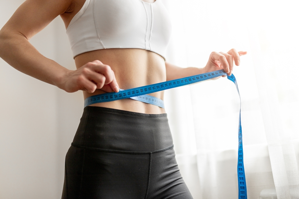 Woman measuring her waist after medical weight loss in Ellicott City MD at Lizabelly Medspa