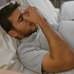 Young man lying in bed with restless sleep representing how poor sleep and testosterone quality
